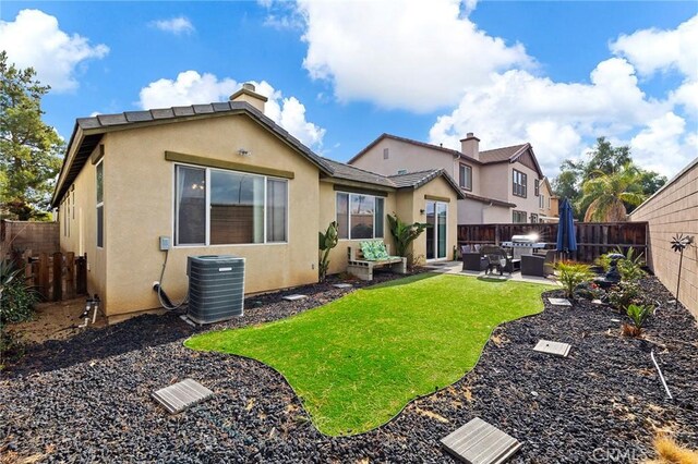 rear view of house featuring a yard, central AC unit, and a patio area