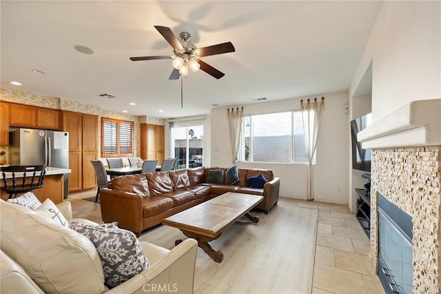 living room with ceiling fan and a stone fireplace