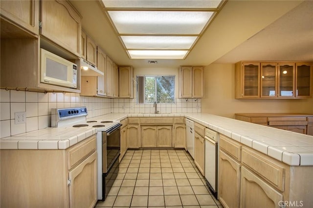 kitchen featuring light brown cabinetry, sink, white appliances, and tile counters