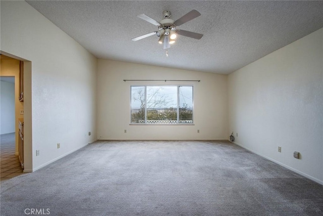 carpeted spare room featuring ceiling fan, vaulted ceiling, and a textured ceiling