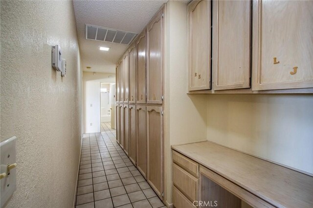 hall featuring light tile patterned floors and a textured ceiling