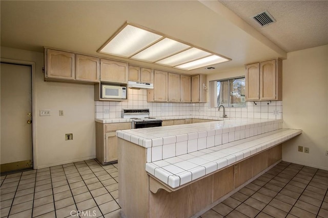 kitchen featuring sink, white appliances, tile countertops, kitchen peninsula, and light brown cabinets