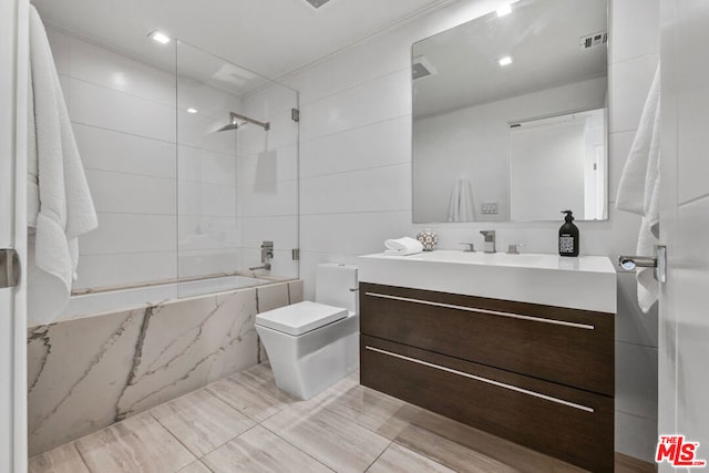 bathroom with vanity, tile walls, and toilet