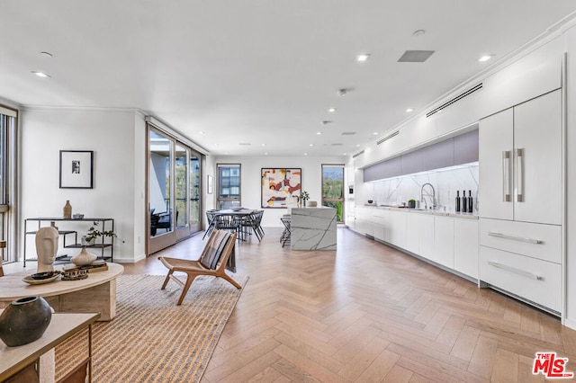 living room featuring sink, ornamental molding, and light parquet floors