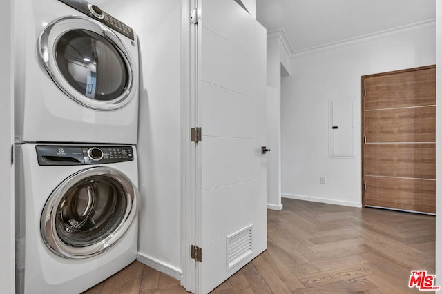 clothes washing area featuring parquet floors, stacked washing maching and dryer, electric panel, and crown molding