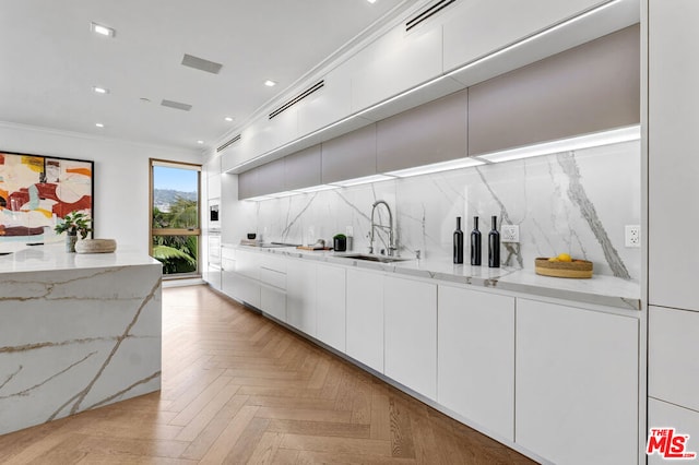 kitchen featuring light stone countertops, sink, and white cabinets