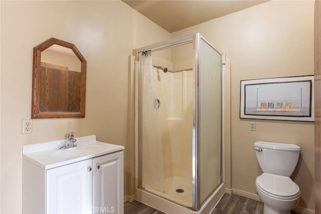 bathroom featuring hardwood / wood-style flooring, toilet, vanity, and a shower with shower door