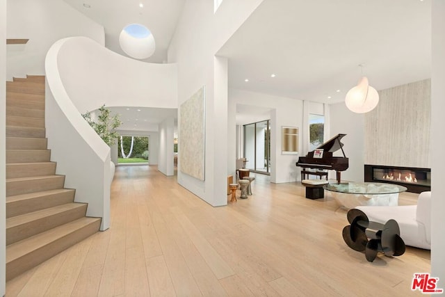 entrance foyer with a fireplace, light hardwood / wood-style floors, and a high ceiling