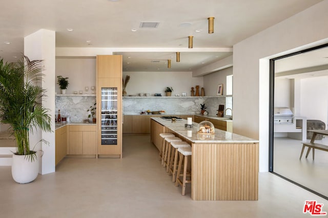 kitchen featuring light brown cabinetry, tasteful backsplash, a breakfast bar, and a kitchen island