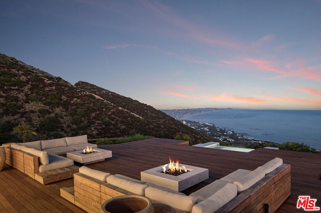 deck at dusk with a water and mountain view and a fire pit