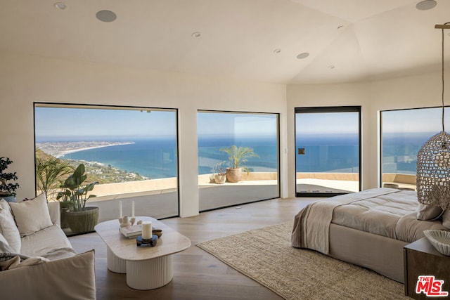 bedroom featuring hardwood / wood-style flooring, a water view, access to outside, and lofted ceiling