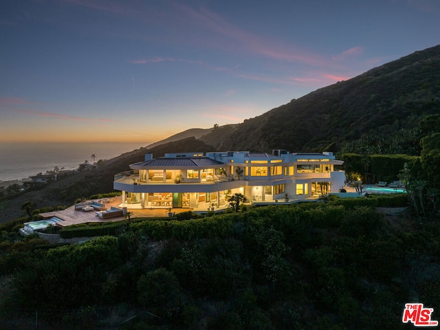 back house at dusk with a balcony and a mountain view