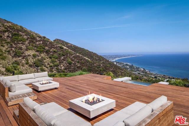 deck with a water view and an outdoor living space with a fire pit