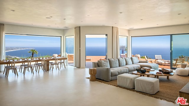 living room with a water view, plenty of natural light, and concrete floors