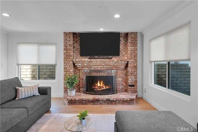 living room with a brick fireplace, hardwood / wood-style flooring, and ornamental molding