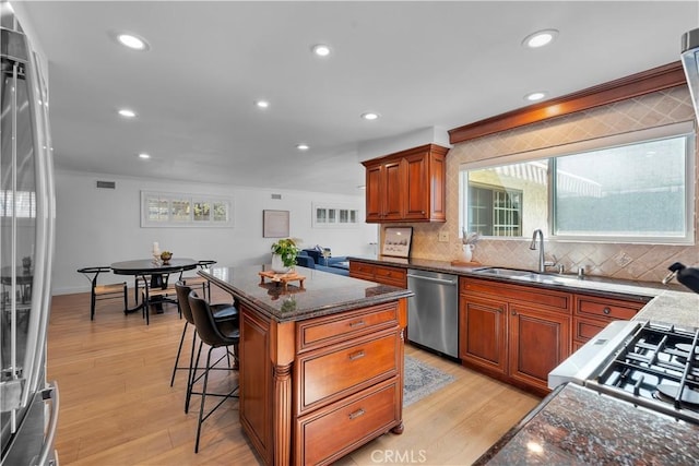 kitchen with sink, stainless steel appliances, light hardwood / wood-style floors, and a kitchen island