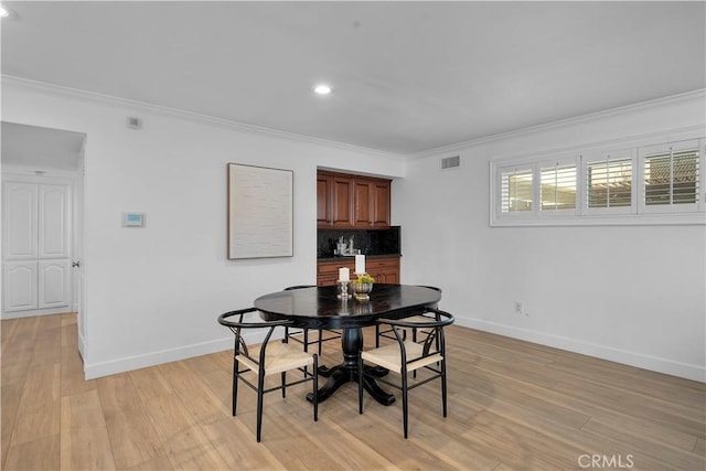 dining room featuring crown molding and light hardwood / wood-style floors