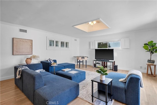 living room with ornamental molding and light hardwood / wood-style flooring