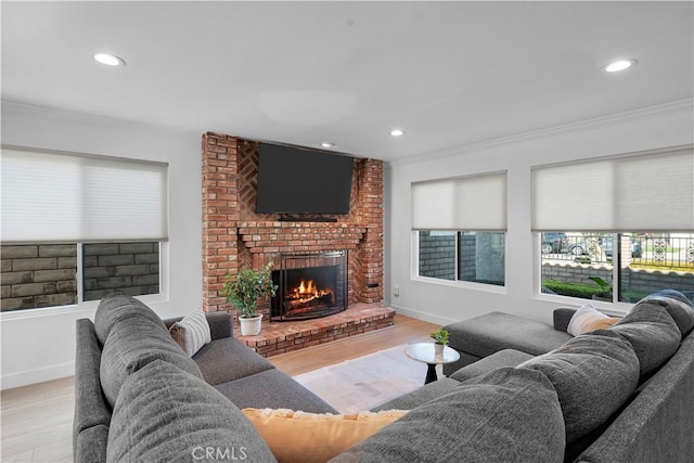 living room with a brick fireplace, crown molding, and light hardwood / wood-style floors