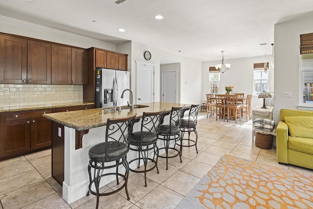 kitchen with stainless steel fridge, sink, and a center island with sink