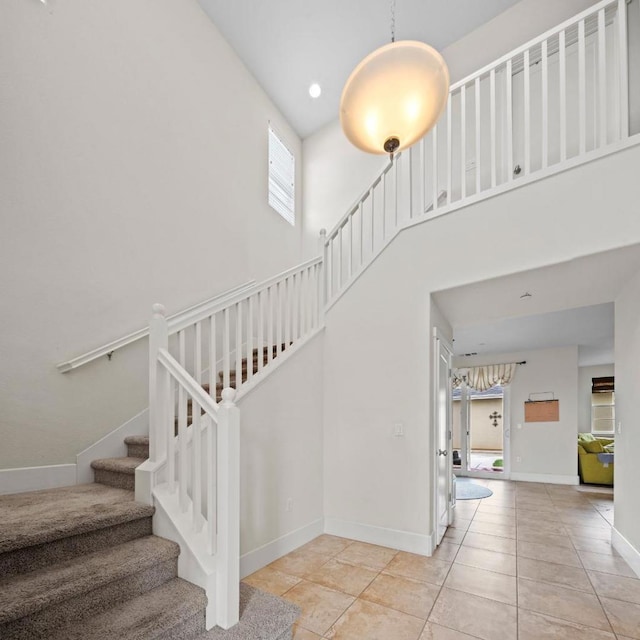 stairs with a towering ceiling and tile patterned floors