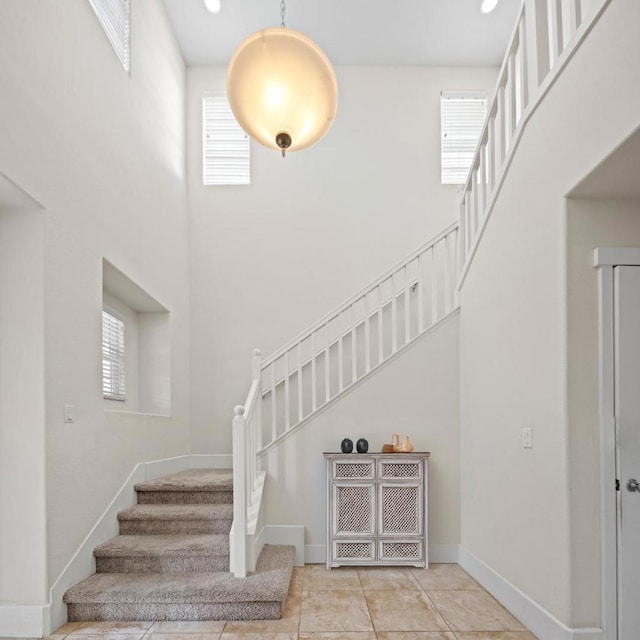 staircase featuring a high ceiling and tile patterned flooring