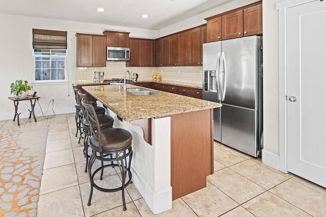 kitchen with tasteful backsplash, an island with sink, sink, a breakfast bar area, and stainless steel appliances