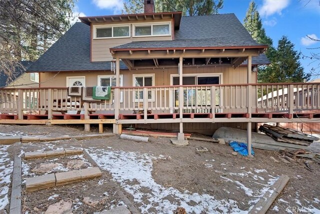 snow covered rear of property with a deck