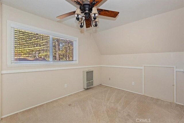 additional living space with vaulted ceiling, heating unit, light colored carpet, and ceiling fan