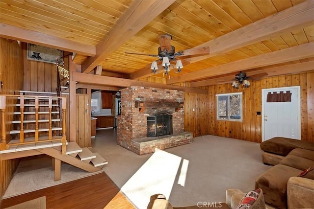 unfurnished living room with beam ceiling, carpet flooring, a fireplace, and wooden walls