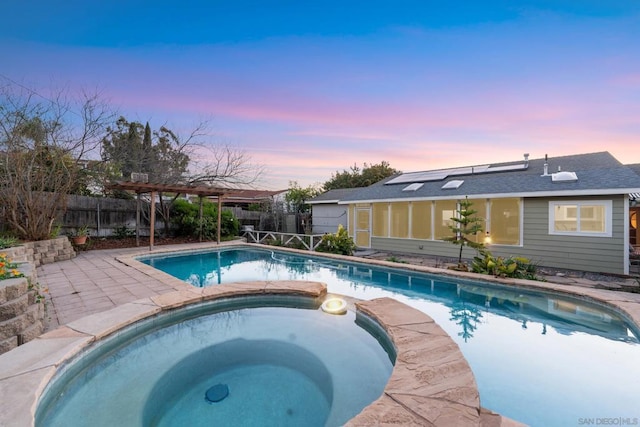 pool at dusk with an in ground hot tub