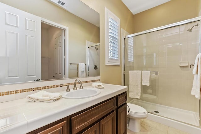 bathroom featuring vanity, tile patterned flooring, a shower with door, and toilet