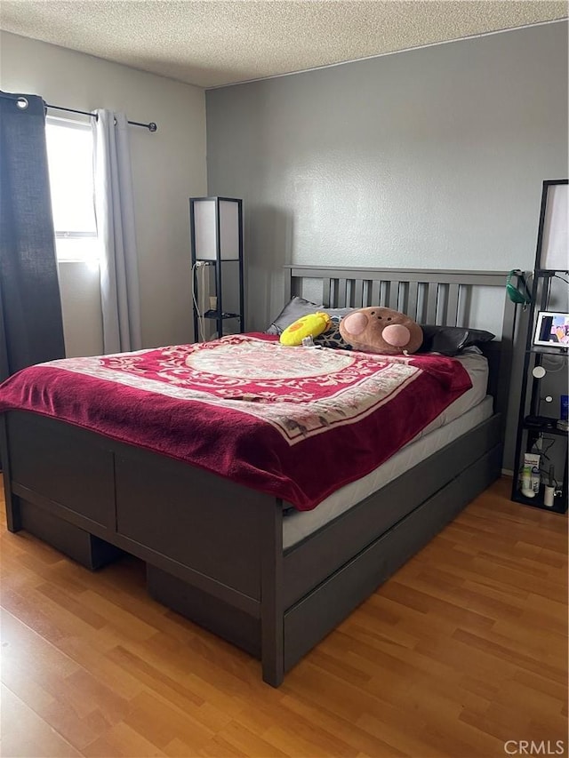 bedroom with hardwood / wood-style floors and a textured ceiling