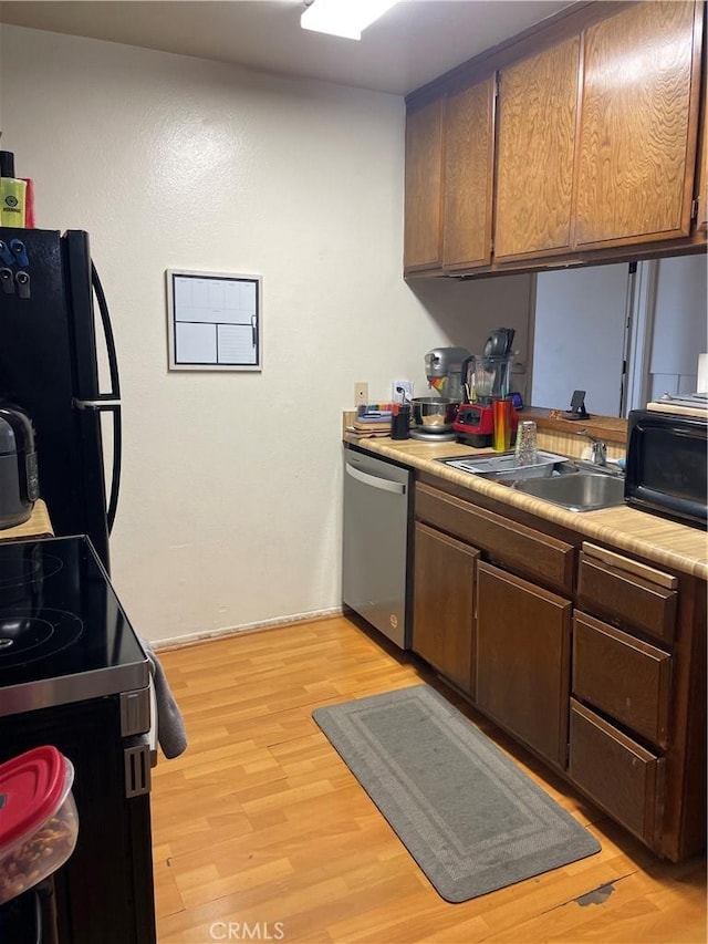 kitchen with sink, black fridge, light hardwood / wood-style flooring, electric range, and stainless steel dishwasher