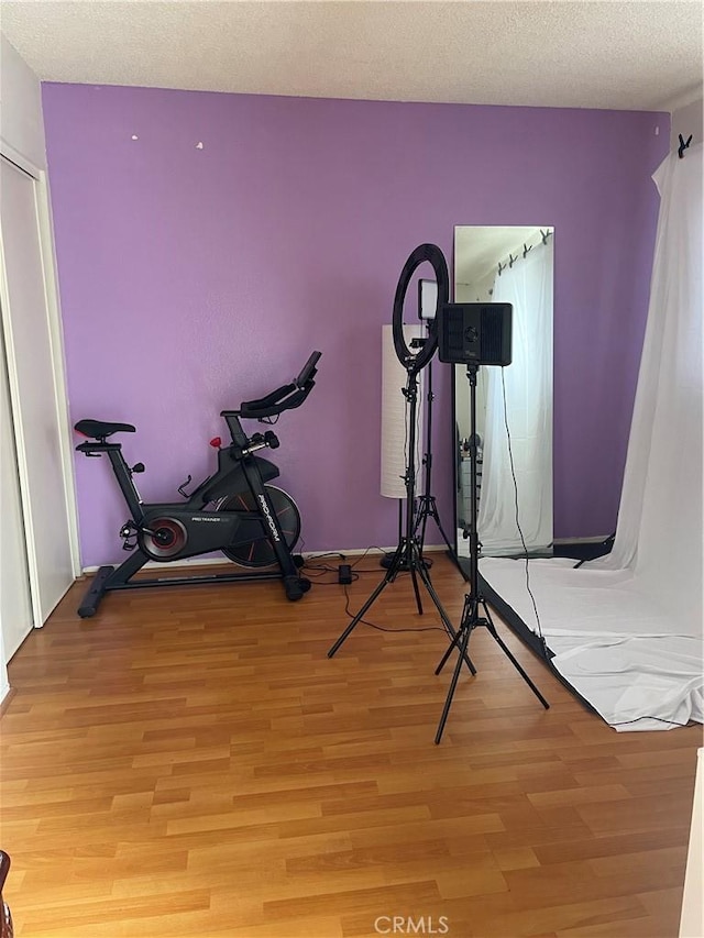 workout room featuring light hardwood / wood-style flooring and a textured ceiling