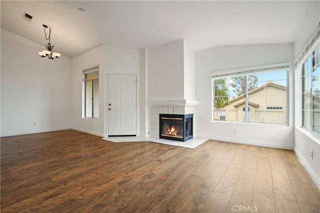 unfurnished living room with an inviting chandelier, lofted ceiling, hardwood / wood-style floors, and a fireplace