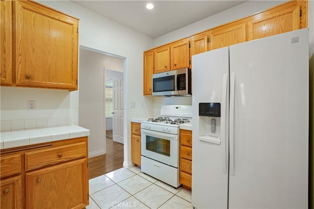 kitchen with light tile patterned flooring, white appliances, and tile countertops