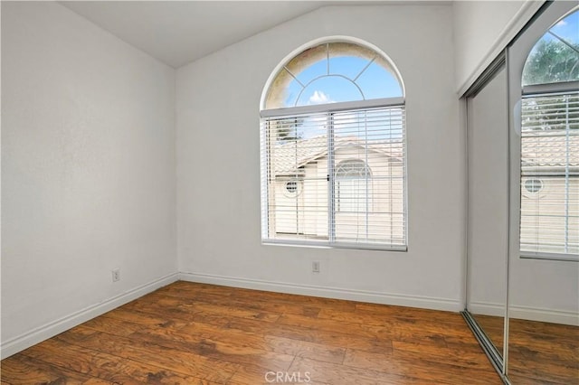 unfurnished room featuring dark hardwood / wood-style flooring and vaulted ceiling