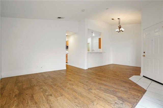 unfurnished room with a notable chandelier, light hardwood / wood-style flooring, and vaulted ceiling