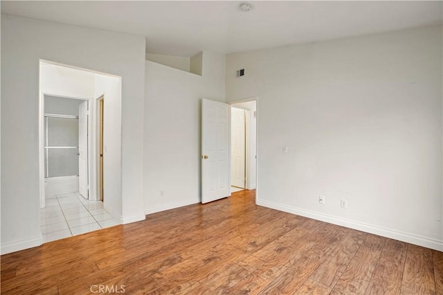 empty room with lofted ceiling and light hardwood / wood-style floors