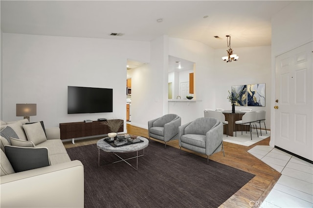 living room featuring lofted ceiling, an inviting chandelier, and light hardwood / wood-style flooring