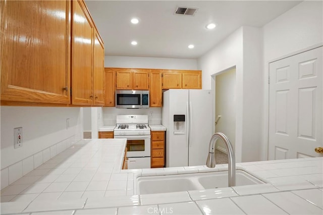 kitchen featuring sink, tile countertops, and white appliances