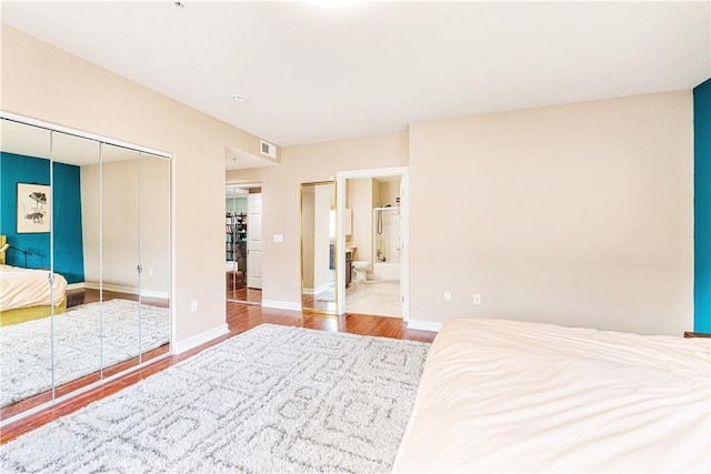 bedroom featuring hardwood / wood-style flooring, ensuite bath, and a closet