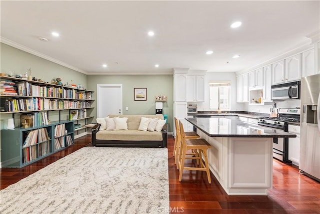 kitchen with dark wood-type flooring, a breakfast bar, a center island, stainless steel appliances, and white cabinets