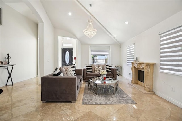 living room featuring lofted ceiling, a notable chandelier, and a fireplace