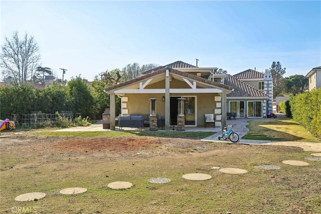 rear view of property featuring outdoor lounge area, a patio, and a lawn