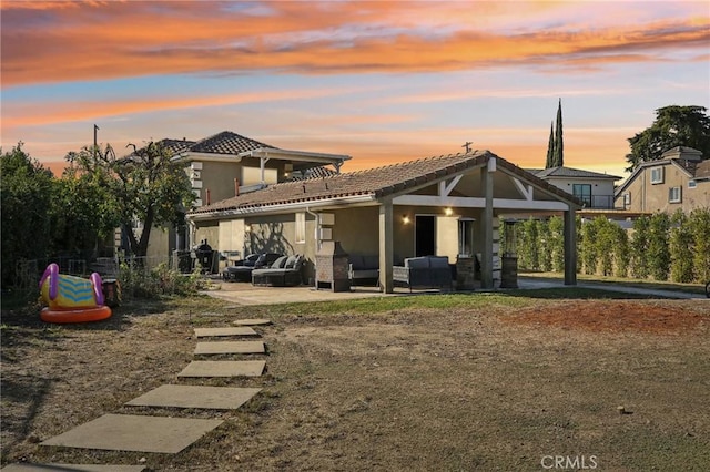 back house at dusk featuring an outdoor living space and a patio area