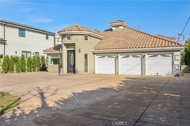 mediterranean / spanish house featuring a garage and central air condition unit