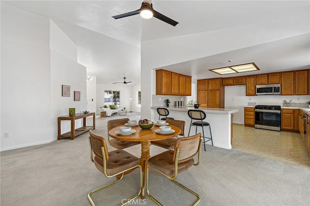 carpeted dining space with ceiling fan and vaulted ceiling