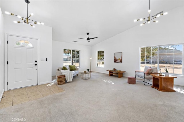 foyer with light carpet, ceiling fan with notable chandelier, plenty of natural light, and high vaulted ceiling